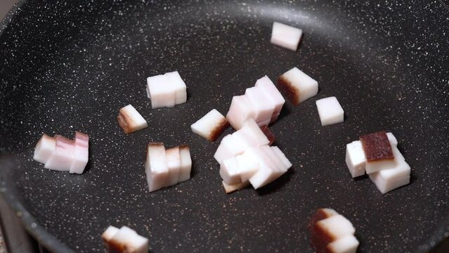 roasting of salted pork fatback on a red-hot pan, close-up
