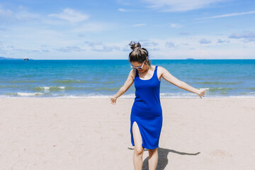 Asian woman walk on the sunny beach with face avoiding the sunlight.