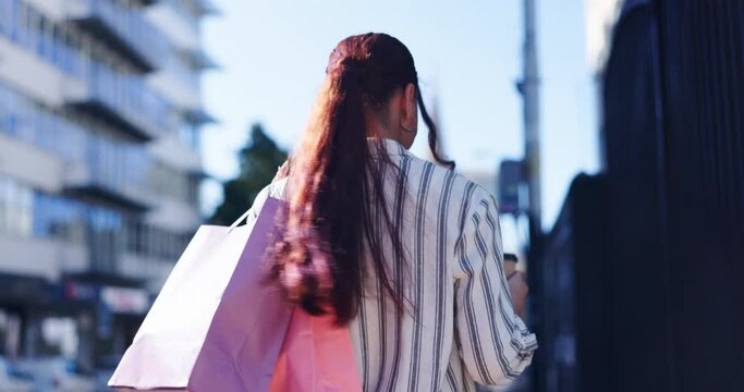 Happy woman, walking and shopping bag in city for discount, sale promotion or outdoor purchase. Rear view of female person or shopper smile in happiness, satisfaction or fashion in an urban town