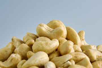Fototapeta na wymiar Large pile of cashew nuts close-up on white background. Packaging design element. Delicious crunchy cashew nuts in close-up laid out in a heap