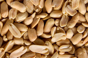 Close-up of the halves of roasted, peeled and salted peanuts for a photophone. Peeled peanuts for a close-up background. A useful source of vegetable protein for vegetarians