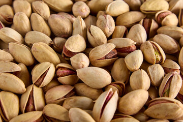 Delicious, mouth-watering fried pistachios in a shell as a background. Close-up of healthy pistachios in a cracked shell, taken from above