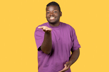 Black man blowing air kiss posing over yellow studio background