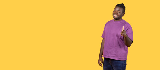 African man pointing finger winking at camera over yellow background