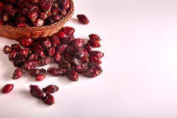 Large red dry rosehip berries are scattered from wicker dishes on a white background. Seasonal superfood in the form of rosehips with health benefits and disease prevention