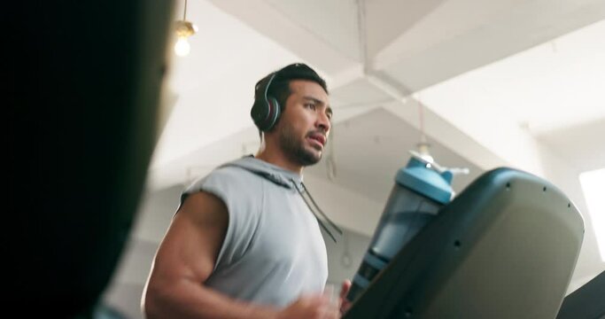 Fitness, watch and man on a treadmill with headphones at gym training for exercise. Profile of Asian athlete person listening to music for running, cardio time or workout on machine for health