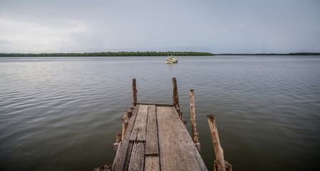 Fototapeta premium fishing boat waiting in front of wooden pier in clouded day