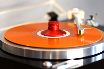 Vintage Stereo Turntable Record Player Tonearm Above Orange Colored Vinyl