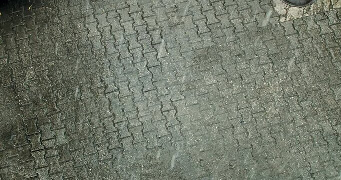 Hail and heavy rain on pavement tiles in the European city, above view