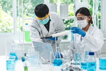 Fototapeta premium Young scientists conducting research investigations in a medical laboratory, a researcher in the foreground, Research and development concept with scientific and medical lab instrument, test tube