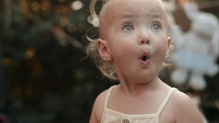 Portrait of a charming adorable and surprised little girl with her toy in the backyard a lot of teddy bears in the Background. Little girl kid enjoys kids party summer days outdoor