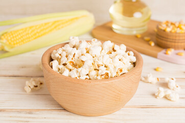 Prepared popcorn with ingredients on wooden table