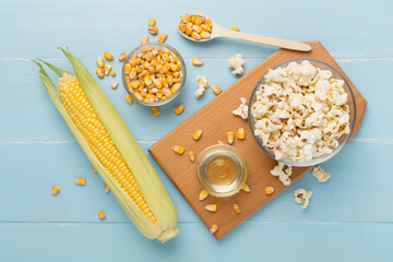 Prepared popcorn with ingredients on wooden background, top view