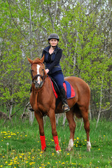 A jockey girl rides a horse on a green meadow