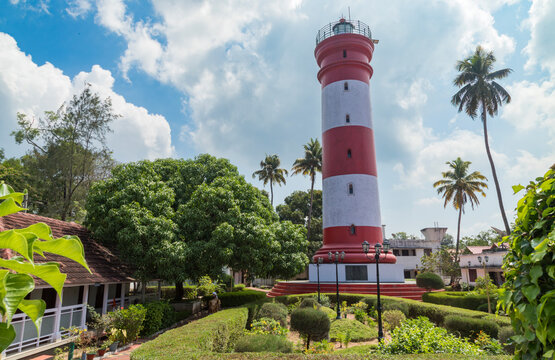 Alleppey Lighthouse with red and white stripes with palm trees on cloudless blue sky, Aleppuzha, Kerala, India