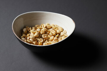 A plate with salted pistachios in a dark room on a dark background. Close-up