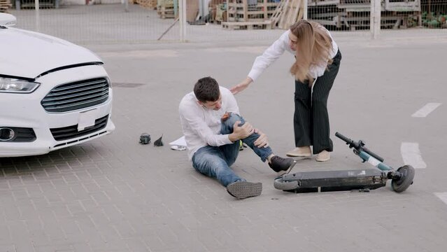 A man riding an electric scooter was hit by a car and fractured his knee screaming in pain. The driver runs towards him nervously and asks why he didn't make sure when he crossed the intersection