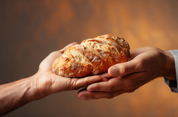 Two hands holding bread on brown gold background