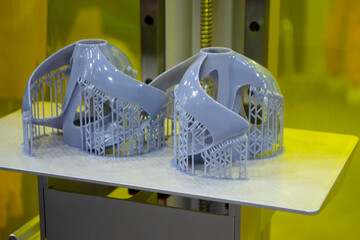 Printed models on 3D printer close-up. Objects printed on photopolymer sla 3D printer from liquid photopolymer resins on printing platform inside 3d printer. Modern progressive additive technology.