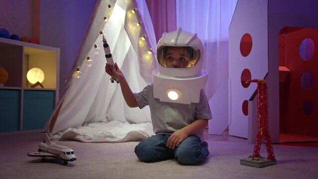 Preschooler boy imagines himself as astronaut playing with rocket during sleepover.