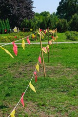 Yellow and red triangular flags strung in the park. Activities in parks, outdoors.