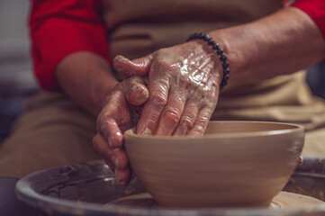 Ceramic plate on a potter's wheel, ceramist's hands.