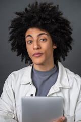 Young curly-haired guy with a laptop in hands looking interested