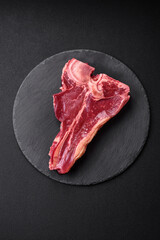 Raw fresh juicy beef t-bone steak with salt, spices and herbs