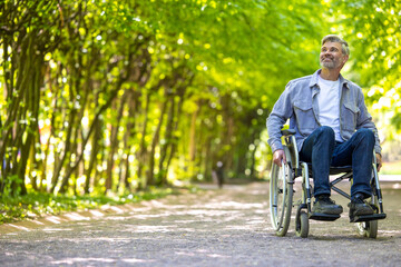 Attractive man in wheelchair resting in park enjoying nature.