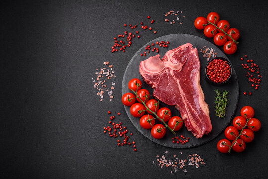 Raw fresh juicy beef t-bone steak with salt, spices and herbs