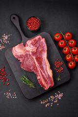 Raw fresh juicy beef t-bone steak with salt, spices and herbs