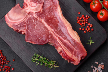 Raw fresh juicy beef t-bone steak with salt, spices and herbs