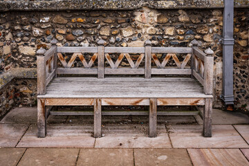 Garden bench in front of flint wall.