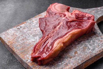 Raw fresh juicy beef t-bone steak with salt, spices and herbs