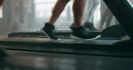 Feet, exercise and running shoes on a treadmill at gym for training and wellness of people. Closeup legs of athlete group together for cardio workout on machine for health, speed and fitness