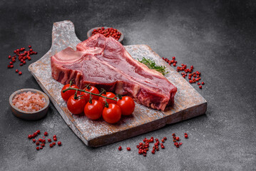 Raw fresh juicy beef t-bone steak with salt, spices and herbs