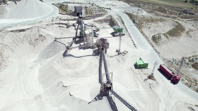 Aerial view of tipper trucks, conveyors, silos and other structures of open pit limestone mine. Construction materials production. Stone crushing plant aerial view.
