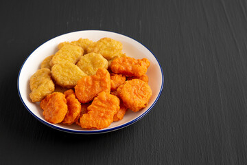 Homemade Spicy Chicken Nuggets Mix on black background, side view. Copy space.