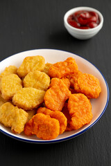 Homemade Spicy Chicken Nuggets Mix on black background, side view.