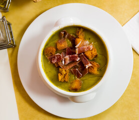 Zucchini soup puree garnished with toasted bread and ham slices