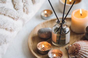 Burning candles on bamboo tray, cozy home atmosphere. Relaxation, detention zone in the living or bedroom. Stones, sea shells as decor. Apartment natural aroma diffusor with ocean breeze fragrance.