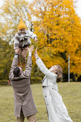 Happy family on a beautiful fall picnic in the park. Cozy autumn vibes. Young father, mother and their cute son spending quality time together, having fun. in the park