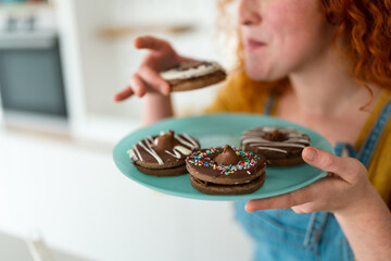 Shot of yummy chocolate sprinkled biscuits in focus while woman holding a mint plate, tasting and...