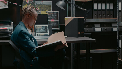 Private detective reading crime information records in police archive room, checking surveillance...