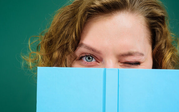 Close up portrait of winking teacher with notepad. School supplies. Back to school. Female college student hiding behind open book. Girl covers face with notebook. Knowledge day. Teacher in classroom.