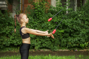 Rhythmic gymnastics. Preteen child exercising with gymnastic mace outdoor. Healthcare concept
