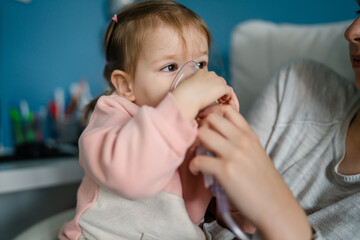 one toddler girl and mother using steam inhaler nebulizer at home - obrazy, fototapety, plakaty