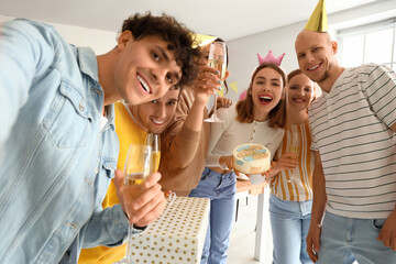 Group of young friends with Birthday cake taking selfie in kitchen