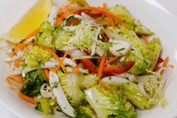 summer seafood salad with octopus, prawns, shrimps, squid, lettuce and tomato in a white bowl