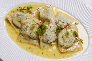 Italian food, mushroom stuffed ravioli pasta with creamy parmesan cheese sauce in a white plate